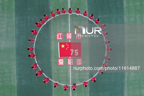 Students pose for a photo with the national flag at the Jindu Huating campus of Xiaoyaojin Primary School in Hefei, China, on September 27,...