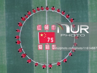 Students pose for a photo with the national flag at the Jindu Huating campus of Xiaoyaojin Primary School in Hefei, China, on September 27,...