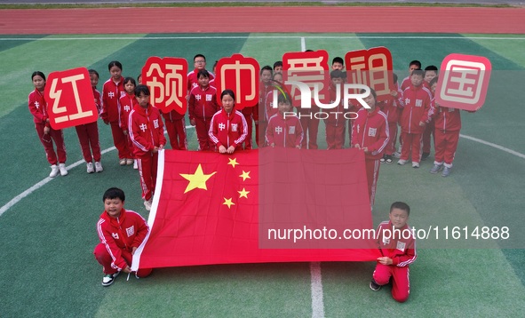 Students pose for a photo with the national flag at the Jindu Huating campus of Xiaoyaojin Primary School in Hefei, China, on September 27,...