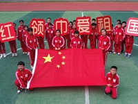 Students pose for a photo with the national flag at the Jindu Huating campus of Xiaoyaojin Primary School in Hefei, China, on September 27,...