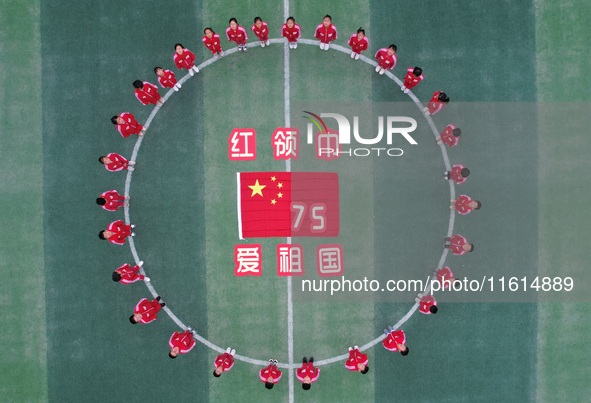 Students pose for a photo with the national flag at the Jindu Huating campus of Xiaoyaojin Primary School in Hefei, China, on September 27,...