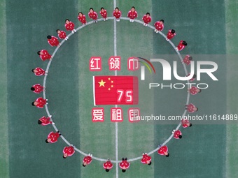 Students pose for a photo with the national flag at the Jindu Huating campus of Xiaoyaojin Primary School in Hefei, China, on September 27,...