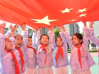 Students pose for a photo with the national flag at the Jindu Huating campus of Xiaoyaojin Primary School in Hefei, China, on September 27,...