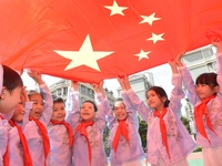 Students pose for a photo with the national flag at the Jindu Huating campus of Xiaoyaojin Primary School in Hefei, China, on September 27,...