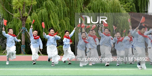 Students run on the playground with a small national flag at the Jindu Huating campus of Xiaoyaojin Primary School in Hefei, China, on Septe...