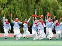 Students run on the playground with a small national flag at the Jindu Huating campus of Xiaoyaojin Primary School in Hefei, China, on Septe...