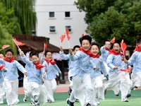 Students run on the playground with a small national flag at the Jindu Huating campus of Xiaoyaojin Primary School in Hefei, China, on Septe...