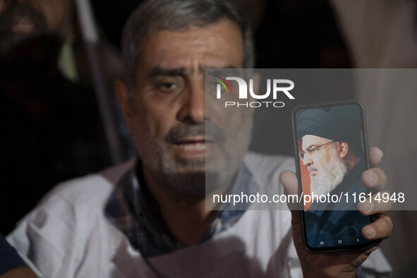 An Iranian protester holds his cellphone featuring a portrait of Lebanon's Hezbollah Secretary General, Hassan Nasrallah, during a protest g...