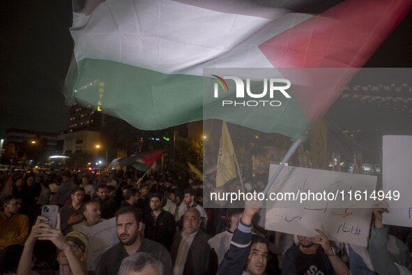 An Iranian protester waves a Palestinian flag while taking part in a protest gathering to condemn an Israeli air strike against Lebanon, in...