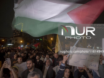 An Iranian protester waves a Palestinian flag while taking part in a protest gathering to condemn an Israeli air strike against Lebanon, in...