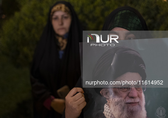 A veiled Iranian protester holds a portrait of Iran's Supreme Leader, Ayatollah Ali Khamenei, while taking part in a protest gathering to co...