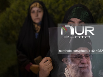 A veiled Iranian protester holds a portrait of Iran's Supreme Leader, Ayatollah Ali Khamenei, while taking part in a protest gathering to co...