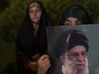 A veiled Iranian protester holds a portrait of Iran's Supreme Leader, Ayatollah Ali Khamenei, while taking part in a protest gathering to co...