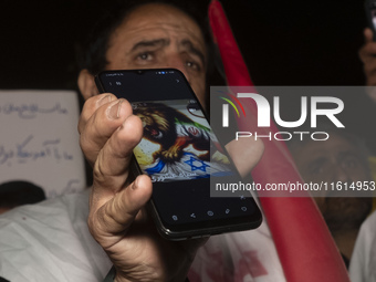 An Iranian protester holds his cellphone featuring an anti-Israeli illustration during a protest gathering to condemn an Israeli air strike...