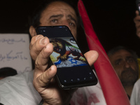 An Iranian protester holds his cellphone featuring an anti-Israeli illustration during a protest gathering to condemn an Israeli air strike...