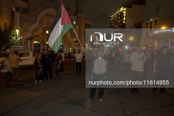 An Iranian protester waves a Palestinian flag while shouting anti-Israeli and anti-U.S. slogans during a protest gathering to condemn an Isr...