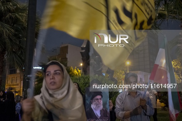 A veiled Iranian protester holds a portrait of Iran's Supreme Leader, Ayatollah Ali Khamenei, while taking part in a protest gathering to co...