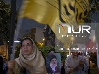 A veiled Iranian protester holds a portrait of Iran's Supreme Leader, Ayatollah Ali Khamenei, while taking part in a protest gathering to co...