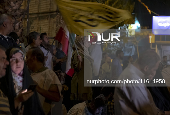 An Iranian female protester waves a flag while taking part in a protest gathering to condemn an Israeli air strike against Lebanon in Tehran...