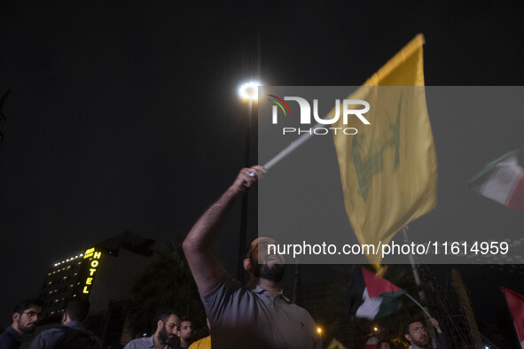 An Iranian protester waves a flag of Lebanon's Hezbollah while taking part in a protest gathering to condemn an Israeli air strike against L...