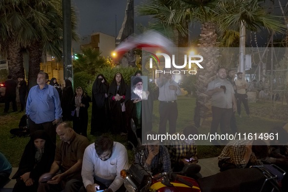 A veiled Iranian protester holds a portrait of Iran's Supreme Leader, Ayatollah Ali Khamenei, while taking part in a protest gathering to co...