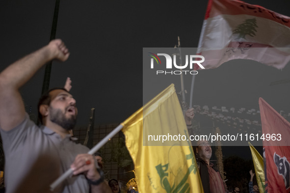 An Iranian protester waves a flag of Lebanon's Hezbollah while shouting anti-Israeli and anti-U.S. slogans during a protest gathering to con...