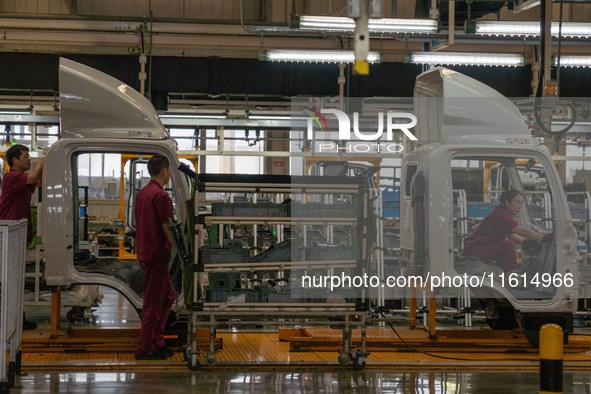 Workers work on a vehicle assembly line at a light truck workshop of Anhui Jianghuai Automobile Group Co LTD in Hefei, China, on September 2...