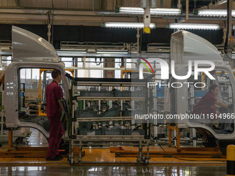 Workers work on a vehicle assembly line at a light truck workshop of Anhui Jianghuai Automobile Group Co LTD in Hefei, China, on September 2...