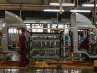 Workers work on a vehicle assembly line at a light truck workshop of Anhui Jianghuai Automobile Group Co LTD in Hefei, China, on September 2...