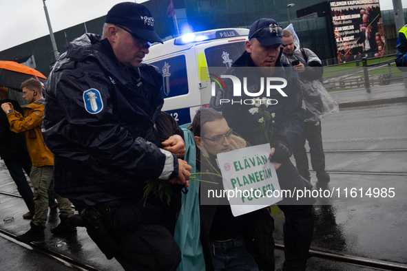 A police officer carries an activist from the environmental group Extinction Rebellion Finland ''Elokapina'' during a protest in front of th...