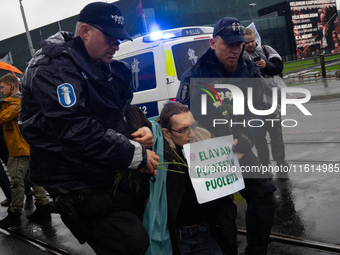 A police officer carries an activist from the environmental group Extinction Rebellion Finland ''Elokapina'' during a protest in front of th...