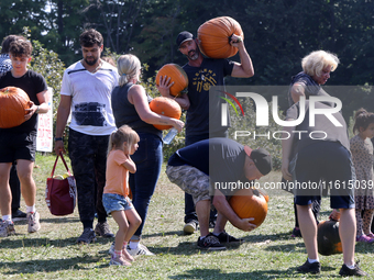 People carry freshly picked pumpkins from a pumpkin patch at a farm in Stouffville, Ontario, Canada, on September 22, 2024. (