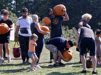 People carry freshly picked pumpkins from a pumpkin patch at a farm in Stouffville, Ontario, Canada, on September 22, 2024. (