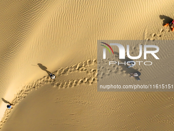 Tourists visit the ''Langsha Mountain'' scenic spot section of the desert highway in Bazhou, Xinjiang, China, on September 23, 2024. (