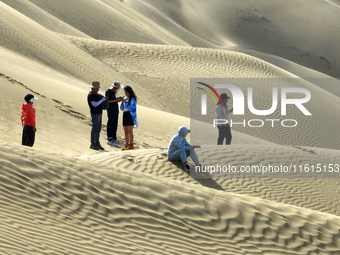 Tourists visit the ''Langsha Mountain'' scenic spot section of the desert highway in Bazhou, Xinjiang, China, on September 23, 2024. (