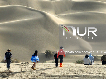 Tourists visit the ''Langsha Mountain'' scenic spot section of the desert highway in Bazhou, Xinjiang, China, on September 23, 2024. (