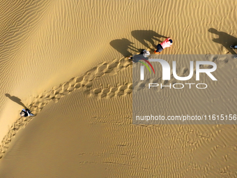 Tourists visit the ''Langsha Mountain'' scenic spot section of the desert highway in Bazhou, Xinjiang, China, on September 23, 2024. (