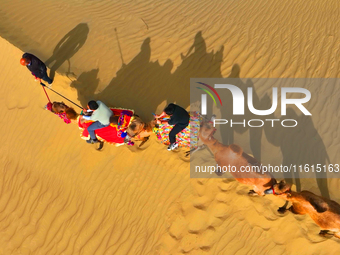 Tourists ride camels to view the scenery of nature in Bazhou, Xinjiang, China, on September 23, 2024. (