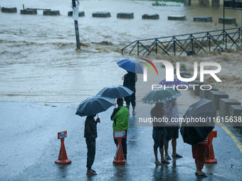 Residents of Kathmandu stand on the embankment of a flooded river in Kathmandu, Nepal, on September 28, 2024, after an overnight heavy downp...