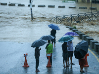 Residents of Kathmandu stand on the embankment of a flooded river in Kathmandu, Nepal, on September 28, 2024, after an overnight heavy downp...