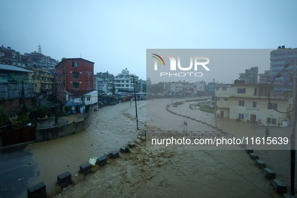 Residents of Kathmandu stand on the embankment of a flooded river in Kathmandu, Nepal, on September 28, 2024, after an overnight heavy downp...