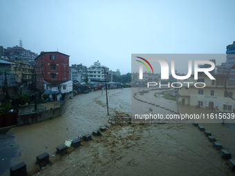 Residents of Kathmandu stand on the embankment of a flooded river in Kathmandu, Nepal, on September 28, 2024, after an overnight heavy downp...