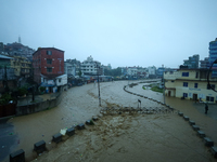 Residents of Kathmandu stand on the embankment of a flooded river in Kathmandu, Nepal, on September 28, 2024, after an overnight heavy downp...