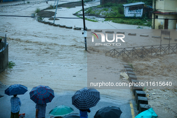 Residents of Kathmandu stand on the embankment of a flooded river in Kathmandu, Nepal, on September 28, 2024, after an overnight heavy downp...