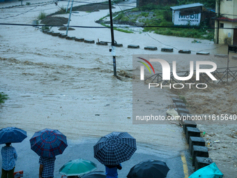 Residents of Kathmandu stand on the embankment of a flooded river in Kathmandu, Nepal, on September 28, 2024, after an overnight heavy downp...