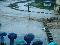 Residents of Kathmandu stand on the embankment of a flooded river in Kathmandu, Nepal, on September 28, 2024, after an overnight heavy downp...