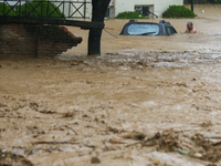 A man wades through the flooded river to reach his partially submerged car in Lalitpur, Nepal, on September 28, 2024. At least 32 people die...