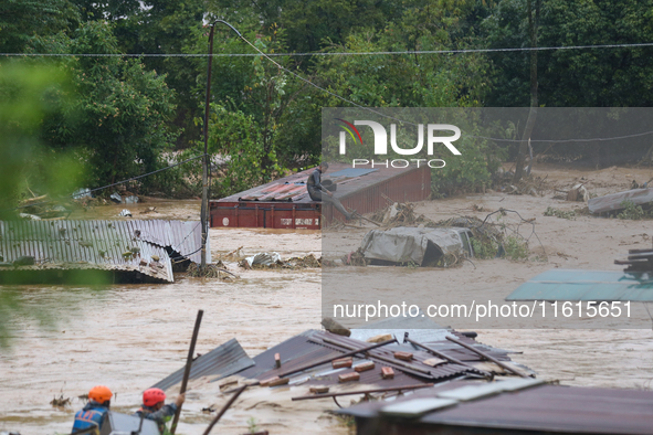 Nepal's Armed Police Force personnel attempt to reach a stranded person from a flooded river in Lalitpur, Nepal, on September 28, 2024. At l...