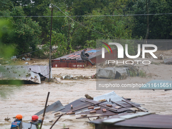 Nepal's Armed Police Force personnel attempt to reach a stranded person from a flooded river in Lalitpur, Nepal, on September 28, 2024. At l...