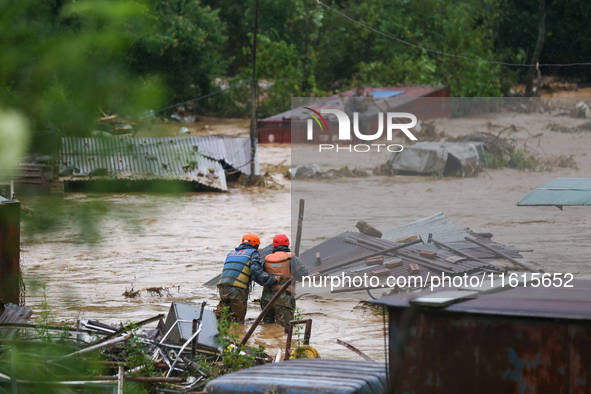 Nepal's Armed Police Force personnel attempt to reach a stranded person from a flooded river in Lalitpur, Nepal, on September 28, 2024. At l...